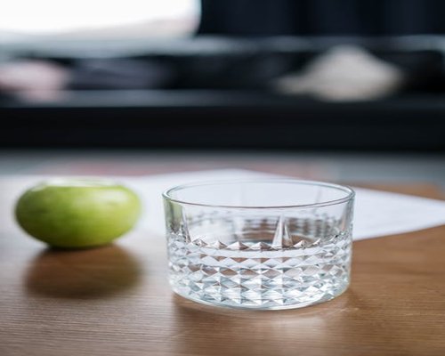 A glass of pure water and fresh fruits on a light wooden table inside a cozy family house